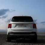 the back end of a white car parked on a rocky beach