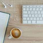 coffee latte near white wireless keyboard and Apple EarPods on the table photography
