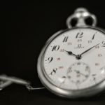 A silver pocket watch on a black background