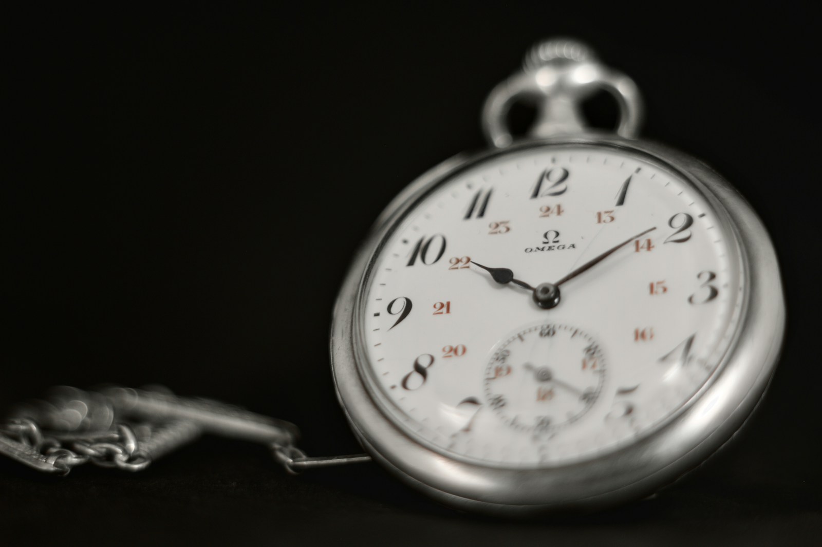 A silver pocket watch on a black background